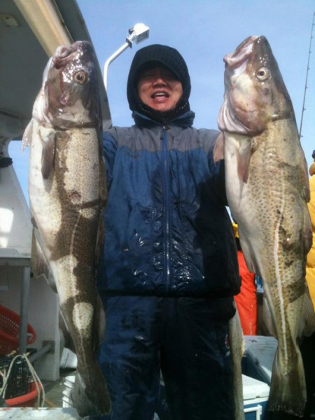Mr. Choi hoisting an impressive pair of codfish caught aboard the Island Current on Sunday. 