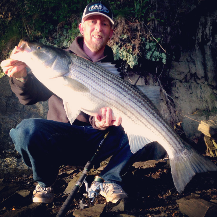 Tim Moore of Suds N' Soda with one of two nice bass he caught from the shore of the Piscatagua River on Monday.