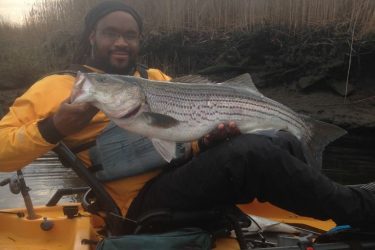 Shawn Barham on his kayak with a great striped bass.