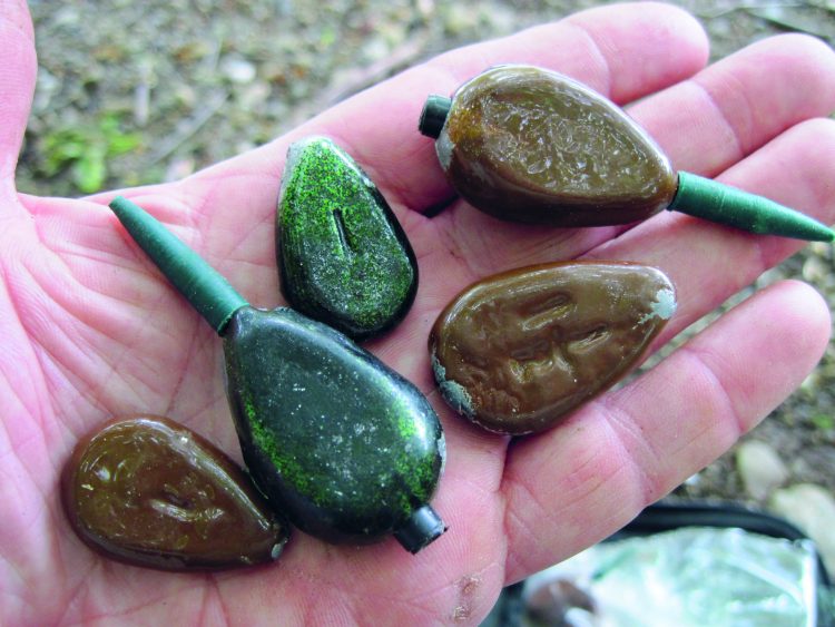 An assortment of carp sinkers, which allow the line to slip through the sinker of the take. Carp fishermen who want to go light on hardware prefer these types of sinkers. Note that they are painted to blend in with the bottom.