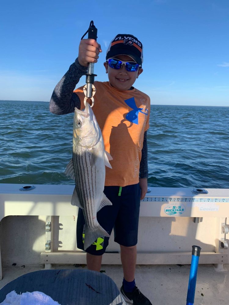 A young angler with a striped bass on Reel Reaction Sportfishing.