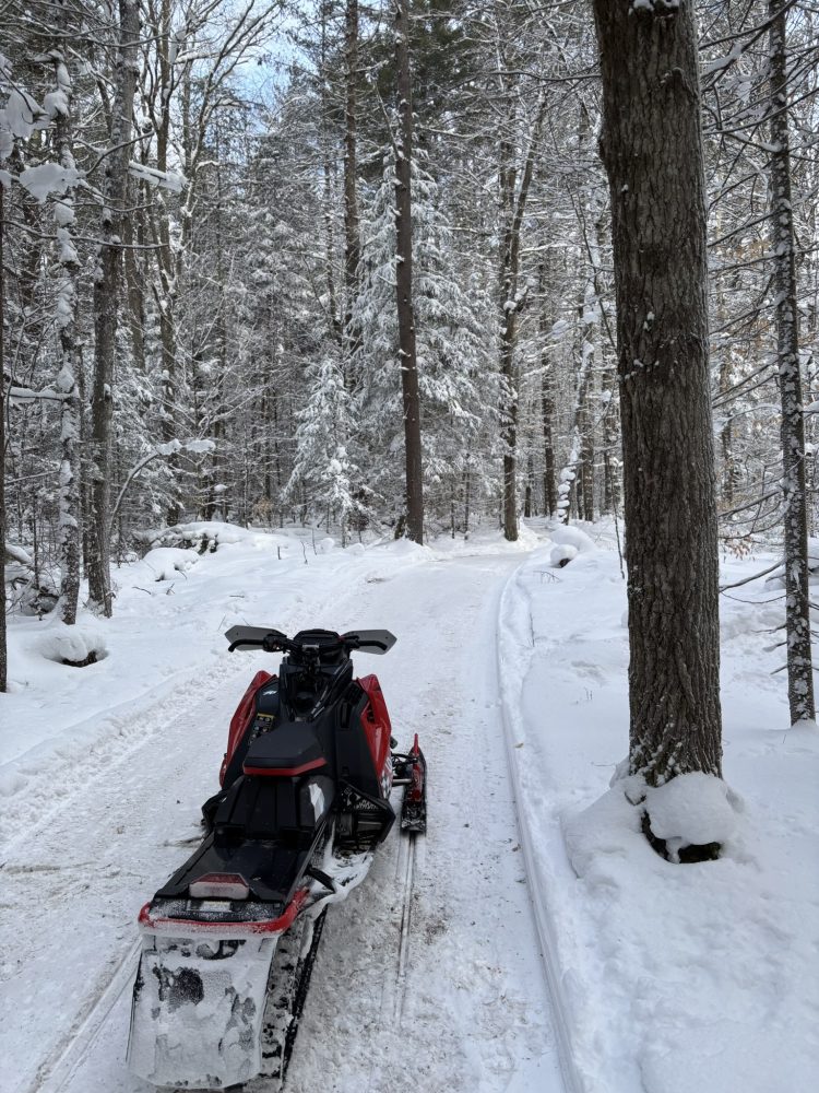 A snowmobile sits on a forest trail in the Adirondack mountains of NY